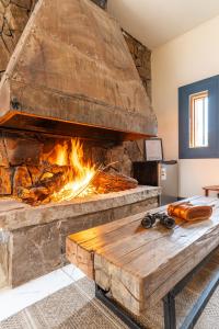 a large stone fireplace with a wooden table in front of it at Lodge Pochoco Refugio de Montaña in Santiago