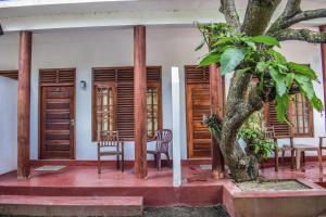 a room with a tree and chairs and wooden doors at Sea Zone Resort in Mirissa