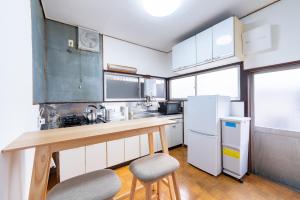 una cocina con armarios blancos y una barra con 2 taburetes en GuestHouse　YOU&I平和島, en Tokio