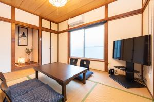 ein Wohnzimmer mit einem Tisch und einem Flachbild-TV in der Unterkunft GuestHouse　YOU&I平和島 in Tokio