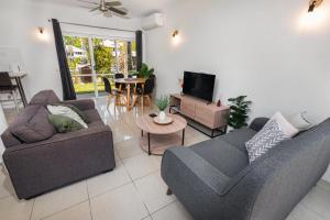 a living room with two couches and a tv at Escape Life @ Port Douglas in Port Douglas