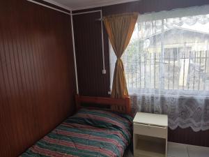 a small bedroom with a bed and a window at Mini cabaña nueva independiente in Temuco