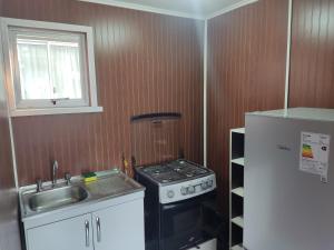 a kitchen with a stove and a sink and a refrigerator at Mini cabaña nueva independiente in Temuco