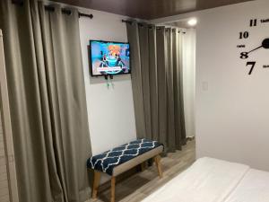 a bedroom with a tv on a wall with curtains at Honey Hill View in San Andrés