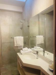 a bathroom with a sink and a shower with a mirror at Serenity Inn Los Chimus in Tortuga