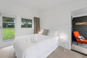 a bedroom with a white bed and a orange chair at Otupai Cottage in Taupo
