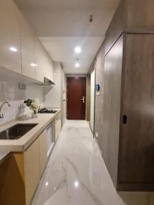 a kitchen with marble flooring and a door to a hallway at Mashley Room Prestige Apartment SKY HOUSE BSD in Cilandak