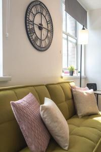 a large clock on the wall above a couch at Amaryllis- 2 Bedroom Flat in Southampton