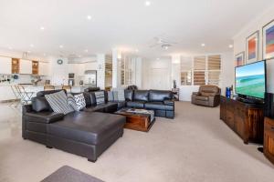 a living room with a couch and a flat screen tv at The Noosa Haven Luxe Waterfront Home in Noosaville