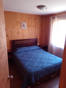 a bedroom with a bed with a blue comforter at Cabañas Marlen in Limache