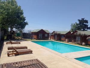 uma piscina com espreguiçadeiras e cadeiras ao lado de uma casa em Cabañas Marlen em Limache