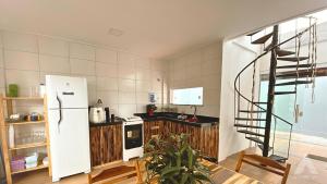 a kitchen with a white refrigerator and a spiral staircase at Viva Guaibim: Casa de Praia com Piscina e Churrasqueira in Guaibim