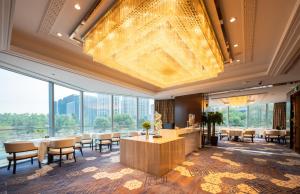 Habitación grande con mesas, sillas y una gran lámpara de araña. en The Grand View Hotel Changzhou en Changzhou