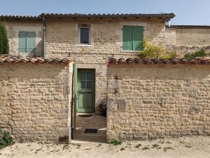une maison en pierre avec une porte verte et un mur en briques dans l'établissement Gîte Coulonges, 3 pièces, 4 personnes - FR-1-653-91, à Coulonges