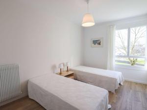 two beds in a white room with a window at Bel appartement rénové, calme, proche centre et plage, balcon, 2 chambres, commerces à 150m - FR-1-4-685 in Saint-Jean-de-Luz