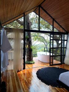 1 dormitorio con ventana grande y bañera en Tree House Glamping, en Yopal