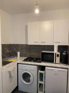 a kitchen with a washing machine and a microwave at Luxsuite in Aubervilliers