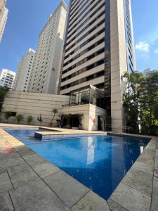 a swimming pool in front of a building with tall buildings at Studio Living Quality Jardins in Sao Paulo