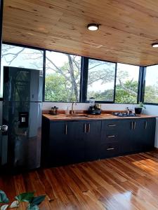 a kitchen with black cabinets and a wooden ceiling at Tree House Glamping in Yopal
