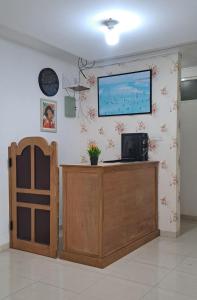 a room with a desk with a television on a wall at ARIMBI GUEST HOUSE in Batu