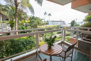 einen Balkon mit einem Tisch, Stühlen und Palmen in der Unterkunft Kantary Bay Hotel Phuket in Panwa Beach