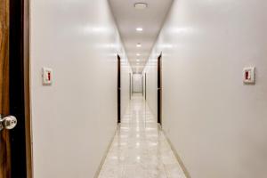 a corridor with white walls and a long hallway with doors at Collection O Dsp Hotels in Ghansoli