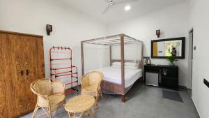 a bedroom with a canopy bed with chairs and a table at E Seven House in Dickwella