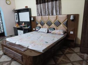 a bedroom with a large bed with a wooden headboard at DHAULADHAR HOMESTAY PALAMPUR in Pālampur
