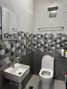 a bathroom with a white toilet and a sink at Paddy View Homestay Kangar in Kangar