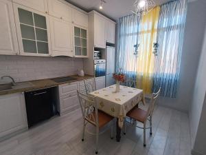 a kitchen with a table and chairs and a kitchen with white cabinets at Апартаменты в ЖК Алау in Taldykolʼ