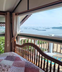 a bedroom with a window looking out at the ocean at Angel house in Ban Tha Thewawong