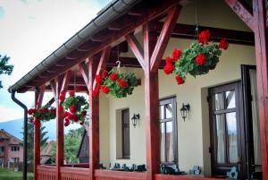 a house with red geraniums hanging from the porch at Amadé Pension & Restaurant in Siculeni