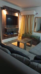 un soggiorno con divano, TV e tavolo di departamento en barrio Roca a Puerto Madryn