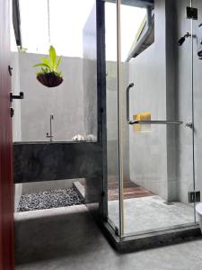 a bathroom with a shower with a plant in it at Ngam Hidden Cabin Room in Thongsala