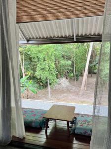Pokój z oknem ze stołem i ławką w obiekcie Ngam Hidden Cabin Room w mieście Thongsala