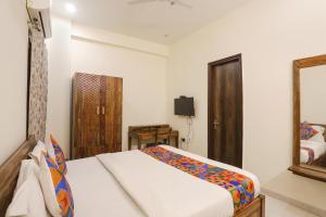 een slaapkamer met een bed en een spiegel bij FabHotel The Avasa in Noida