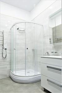 a white bathroom with a shower and a sink at MIRAMAR Apart Hotel & SPA in Aktau