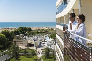 a couple standing on a balcony looking out at the ocean at Laguna Park Hotel 4Superior in Bibione