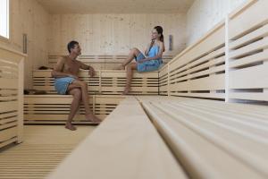 a man and a woman sitting on beds in a large room at Laguna Park Hotel 4Superior in Bibione