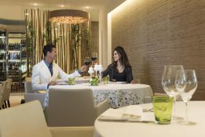a man and woman sitting at a table in a restaurant at Laguna Park Hotel 4Superior in Bibione