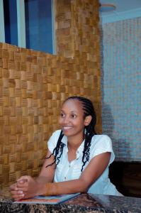 Une femme assise à une table avec les bras croisés dans l'établissement Kinindo Light Hotel, à Bujumbura