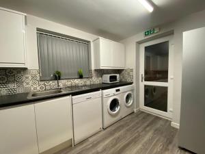 a kitchen with white cabinets and a washer and dryer at Spacious Rooms - Ideal for Contractors Relocators Business Travellers Long Stay Discounts in Parkside
