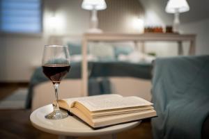 um copo de vinho e um livro aberto sobre uma mesa em Szanna Apartman em Doboz