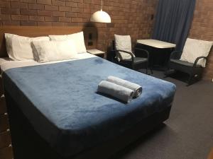 a bedroom with a large bed with two towels on it at Golden West Motor Inn in Miles