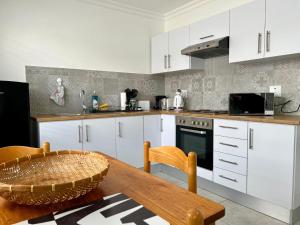 a kitchen with white cabinets and a wooden table at AuobCorner in Walvis Bay