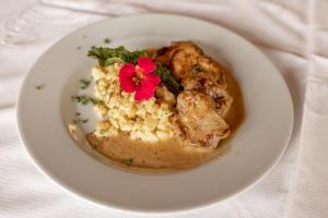a plate of food with mashed potatoes and a red flower at Gasthof Hirschen in Sibratsgfäll