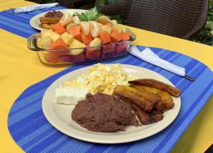 a plate of food with meat and a bowl of fruit at Thermal Paradise Villa in Caluco