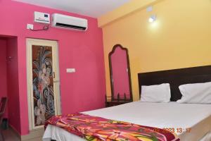 a bedroom with a bed with pink and yellow walls at HOTEL KK BHAWBAN 1IN PURI in Puri