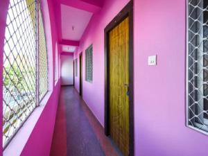 a hallway with pink walls and a wooden door at HOTEL KK BHAWBAN 1IN PURI in Puri