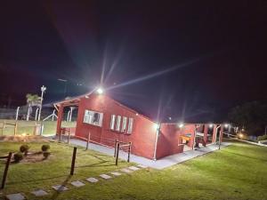 un bâtiment rouge avec des lumières au-dessus de celui-ci la nuit dans l'établissement Pesqueiro & Chácara Moenda, à Itapetininga